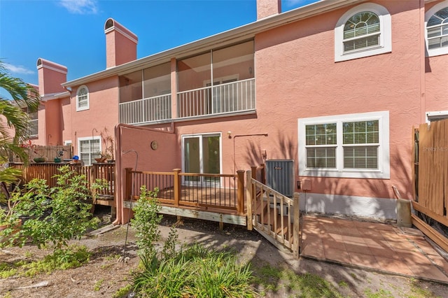 14506 Alejo Ct, Seminole, FL 33776 - back of house featuring a chimney, cooling unit, a wooden deck, and stucco siding