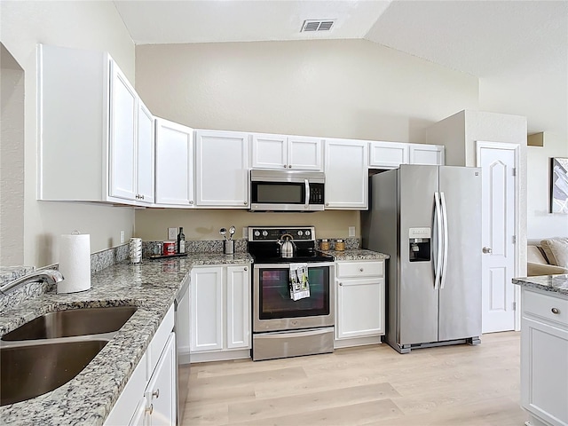 1639 Saddlehorn Dr, Lakeland, FL 33810 - kitchen with visible vents, a sink, light wood finished floors, lofted ceiling, and stainless steel appliances