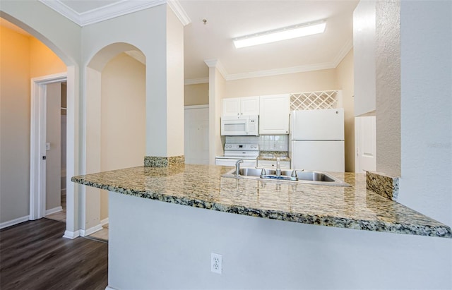 kitchen with tasteful backsplash, light stone counters, a peninsula, dark wood-style floors, and white appliances