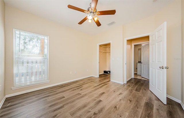unfurnished bedroom with baseboards, wood finished floors, visible vents, and a closet