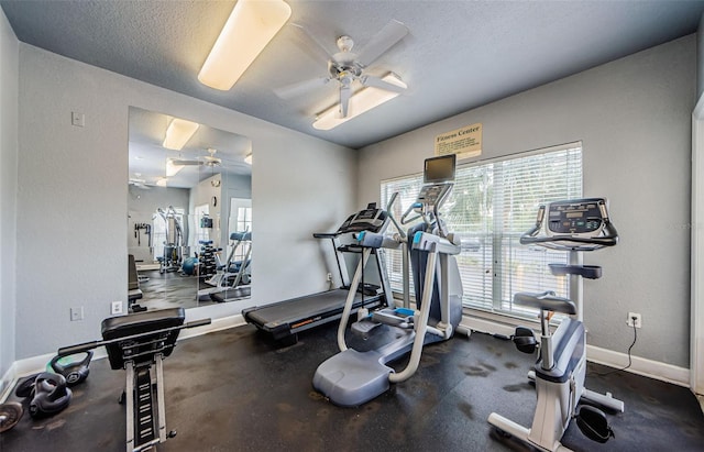 gym featuring baseboards, a ceiling fan, and a textured ceiling
