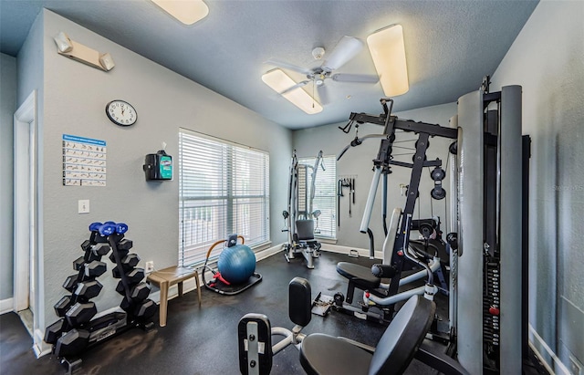 exercise room with baseboards, a textured wall, and ceiling fan