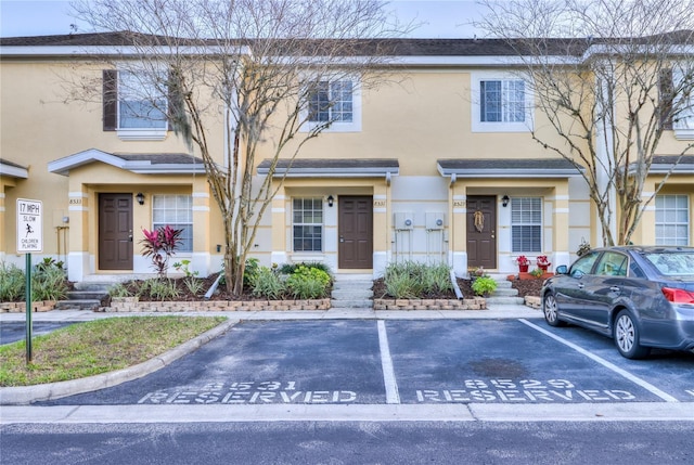view of property featuring uncovered parking and stucco siding