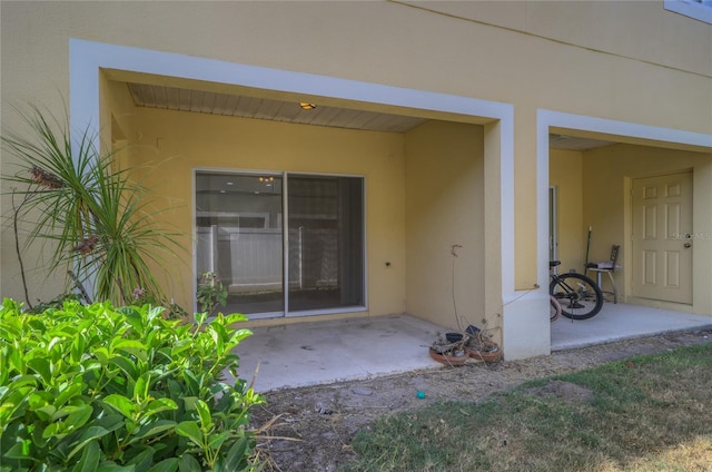 property entrance with stucco siding and a patio area