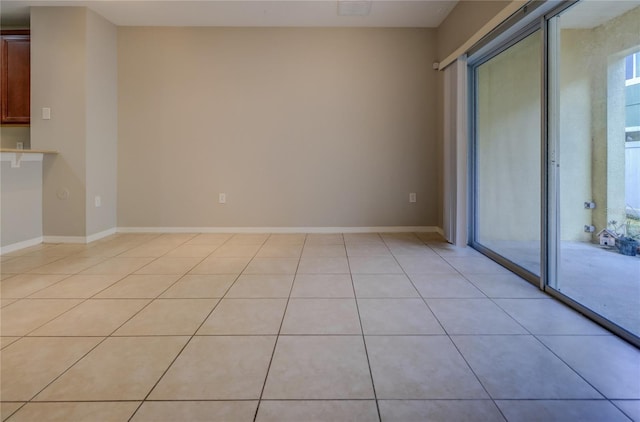spare room featuring baseboards and light tile patterned flooring