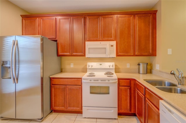 kitchen featuring white appliances, light tile patterned floors, a sink, and light countertops