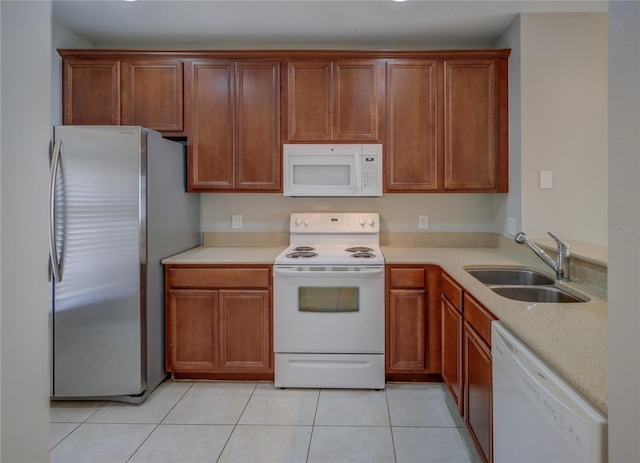 kitchen with a sink, light tile patterned floors, brown cabinets, and white appliances