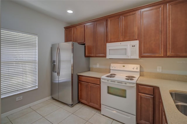 kitchen with light countertops, brown cabinetry, and white appliances