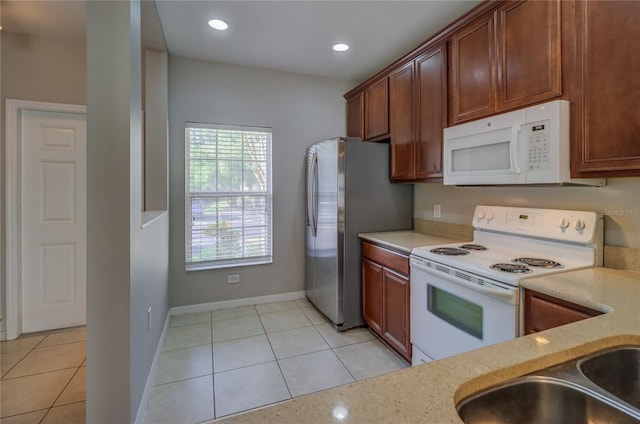 kitchen featuring white appliances, baseboards, recessed lighting, brown cabinets, and light tile patterned floors