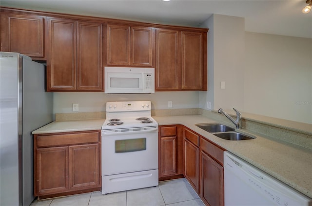 kitchen with white appliances, light tile patterned flooring, a sink, and light countertops
