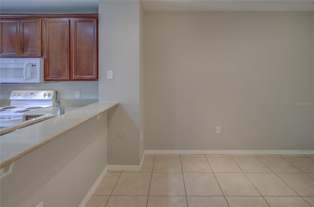 kitchen with white appliances, baseboards, and light tile patterned floors