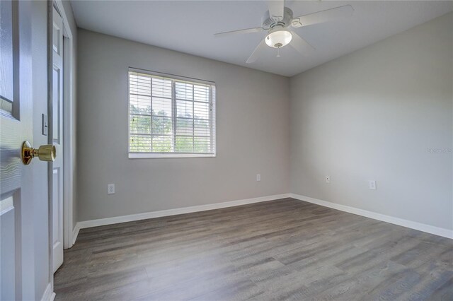 spare room with baseboards, a ceiling fan, and dark wood-style floors