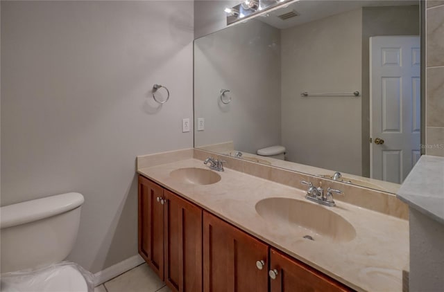 bathroom with double vanity, a sink, tile patterned floors, and toilet