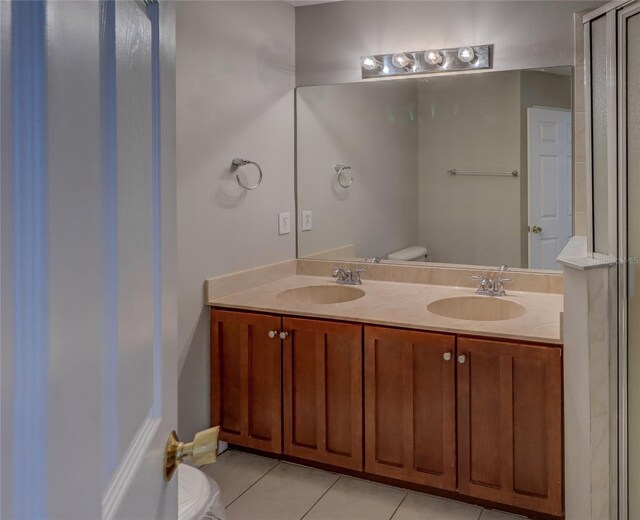 full bath featuring double vanity, toilet, a sink, and tile patterned flooring
