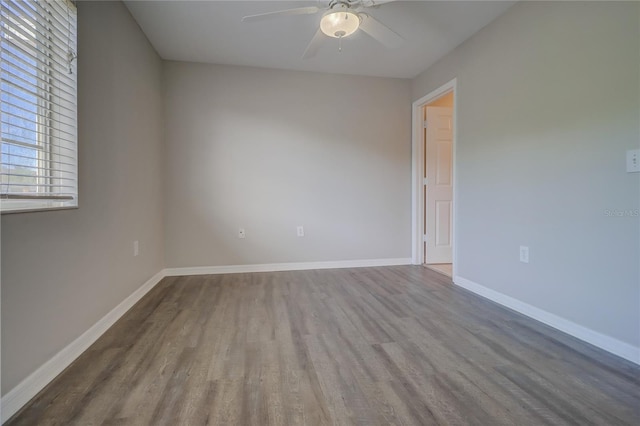 spare room with baseboards, ceiling fan, and wood finished floors