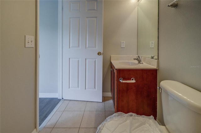half bathroom featuring vanity, baseboards, tile patterned floors, and toilet