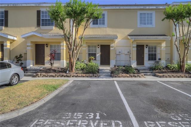 townhome / multi-family property with stucco siding and uncovered parking