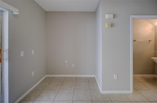 empty room featuring baseboards and light tile patterned flooring