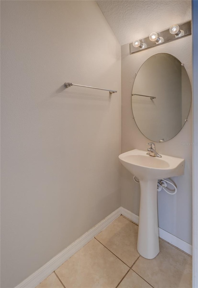 bathroom with a textured ceiling, a sink, baseboards, and tile patterned flooring