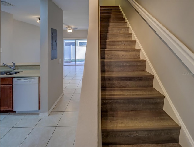 stairway with electric panel, a ceiling fan, visible vents, tile patterned flooring, and baseboards