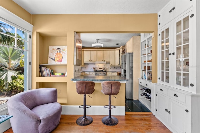 kitchen featuring glass insert cabinets, a peninsula, a breakfast bar, and stainless steel appliances