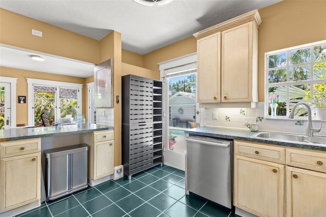 kitchen featuring light brown cabinets, dark countertops, a sink, and dishwasher