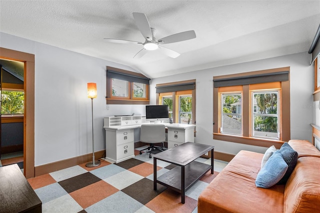 office space featuring baseboards, ceiling fan, a textured ceiling, tile patterned floors, and vaulted ceiling