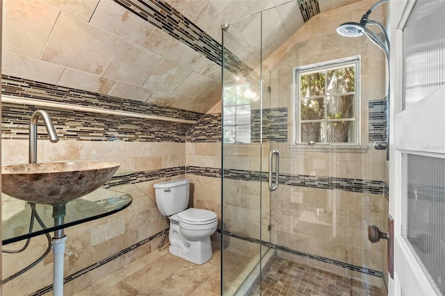 full bathroom featuring a sink, tile walls, a shower stall, and toilet