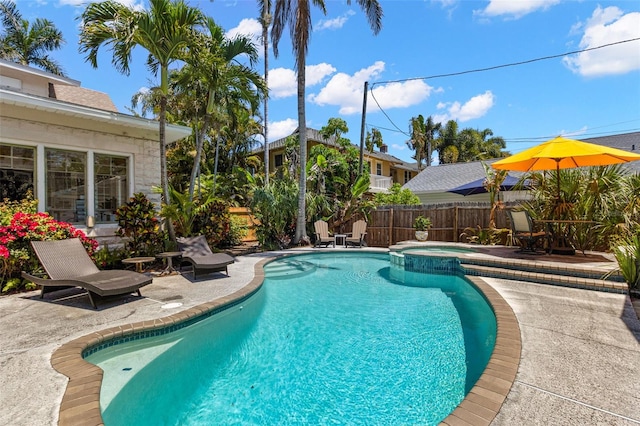 view of pool featuring a patio area, fence, and a pool with connected hot tub