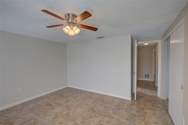 empty room featuring baseboards, a ceiling fan, a textured ceiling, and visible vents