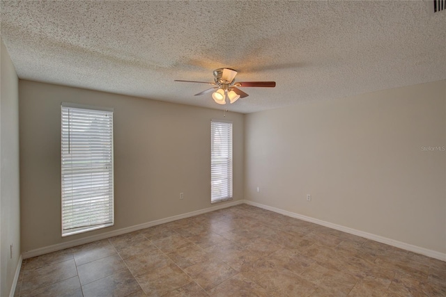 spare room featuring baseboards, plenty of natural light, a ceiling fan, and a textured ceiling