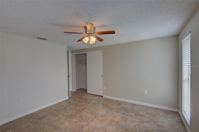 unfurnished bedroom featuring a ceiling fan, a closet, a textured ceiling, and visible vents