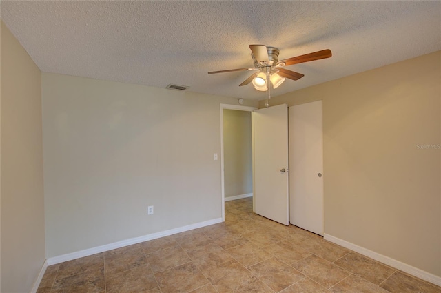 spare room featuring a textured ceiling, ceiling fan, visible vents, and baseboards