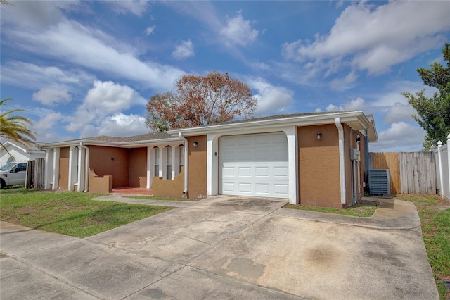 ranch-style home with stucco siding, a garage, fence, and driveway