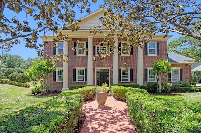 neoclassical home featuring brick siding and a front yard