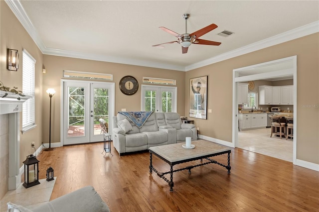 living area with ceiling fan, ornamental molding, french doors, and light wood-type flooring