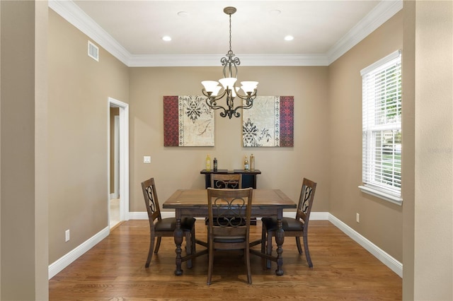 dining area featuring visible vents, ornamental molding, wood finished floors, and a notable chandelier