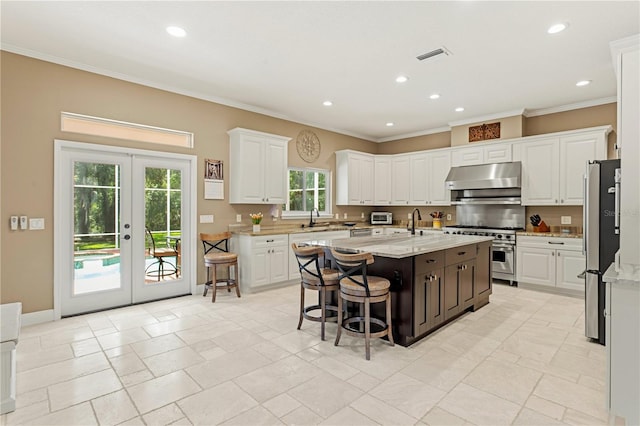 kitchen featuring crown molding, visible vents, white cabinetry, under cabinet range hood, and appliances with stainless steel finishes