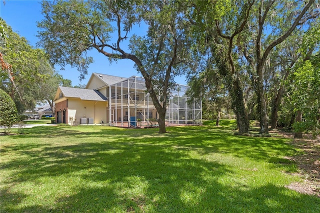 view of yard featuring a garage, a lanai, and central air condition unit