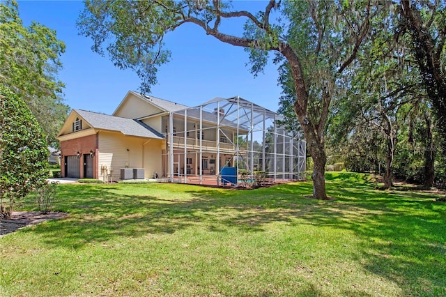 back of property with a lawn, glass enclosure, and an attached garage