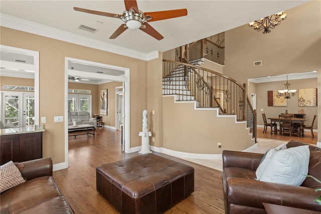 living area featuring stairway, crown molding, ceiling fan with notable chandelier, and visible vents