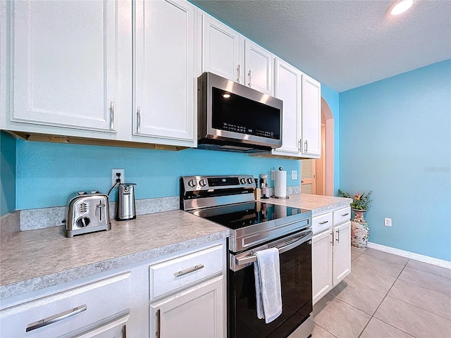 3205 Royal Tern Dr, Winter Haven, FL 33881 - kitchen with light countertops, white cabinetry, light tile patterned flooring, and stainless steel appliances