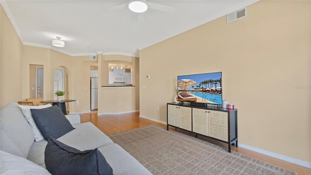 501 Knights Run Ave Unit 1335, Tampa, FL 33602 - living room featuring light wood-style floors, ceiling fan, crown molding, arched walkways, and baseboards