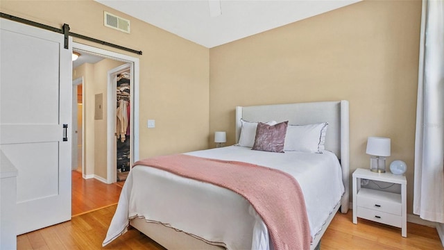 501 Knights Run Ave Unit 1335, Tampa, FL 33602 - bedroom with light wood-style floors, a walk in closet, a barn door, a closet, and a ceiling fan