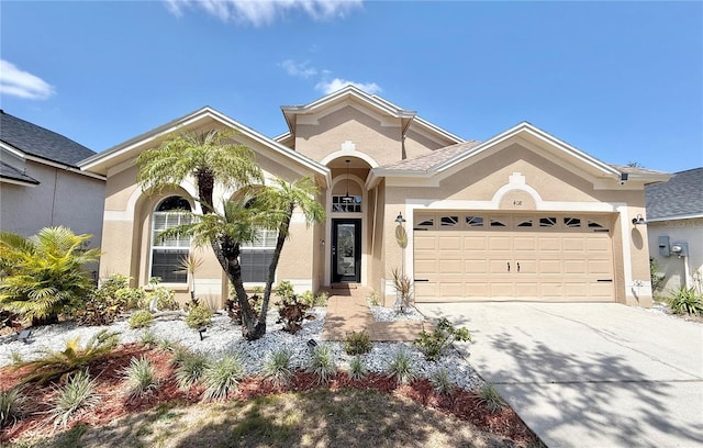 mediterranean / spanish-style house featuring a garage, stucco siding, and driveway