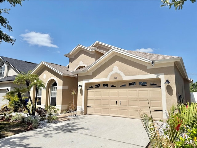 mediterranean / spanish house featuring an attached garage, stucco siding, and driveway