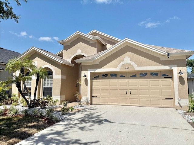mediterranean / spanish-style house with a garage, stucco siding, and concrete driveway