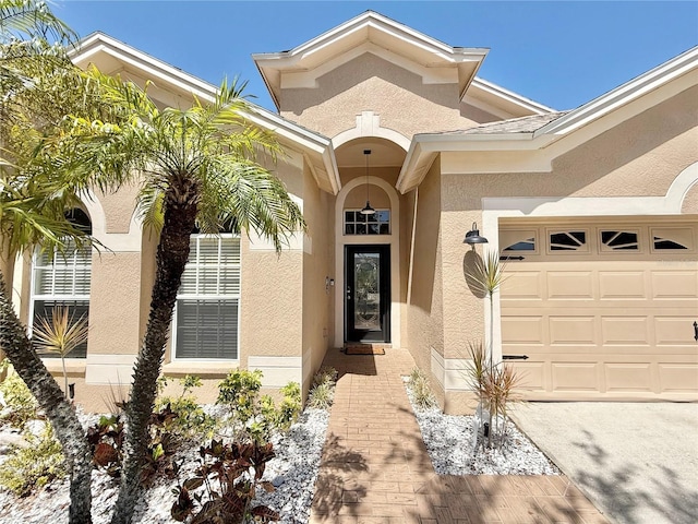 view of exterior entry featuring an attached garage and stucco siding