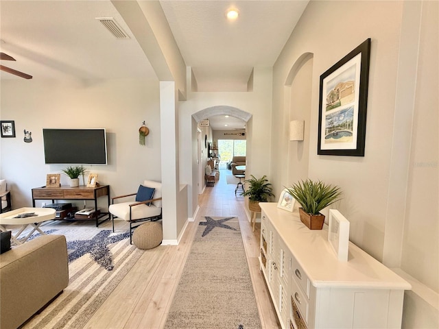hall featuring arched walkways, visible vents, recessed lighting, and light wood finished floors