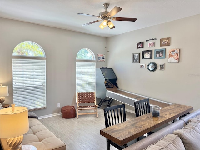 living room featuring a ceiling fan, baseboards, and wood finished floors